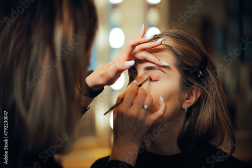 Professional Make-up Artist Applying Eyeshadow with a Brush. Woman having her looks changed through professional makeup 
