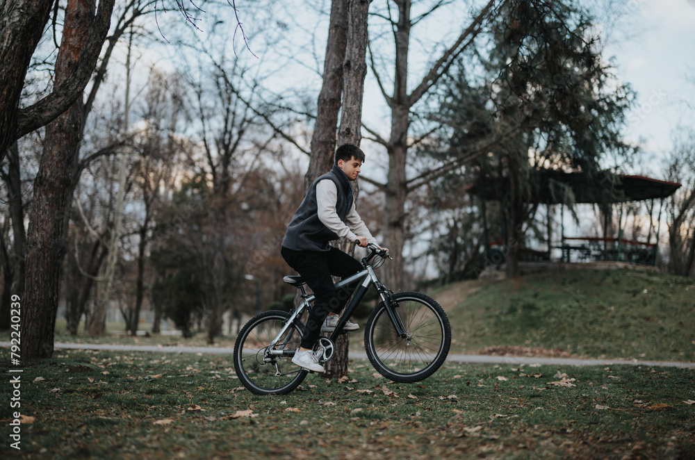 Young male teenager rides his bicycle outdoors, experiencing the joy of leisure time in a natural setting.