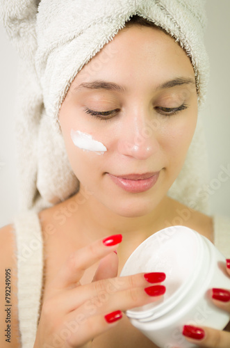 Happy young woman applying serum on her face