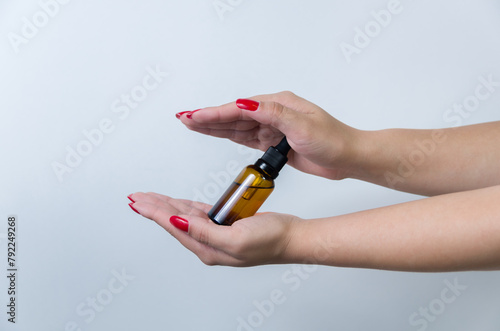 Product package with serum and a woman hand in studio on a background