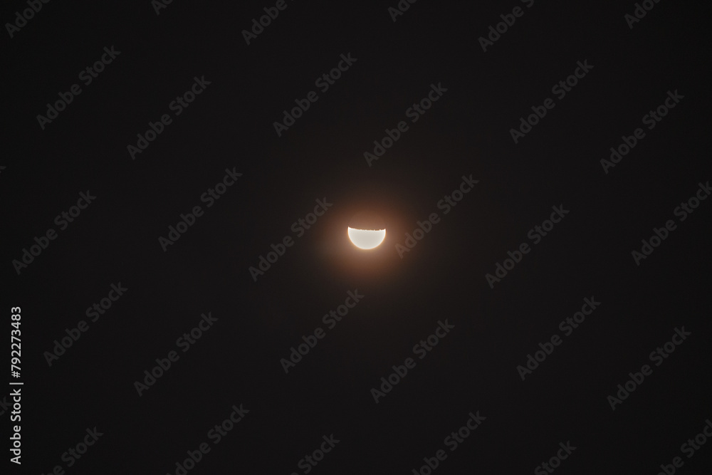 A large moon is in the sky, with a small portion of it lit up A large moon is in the sky, with a small portion of it lit up