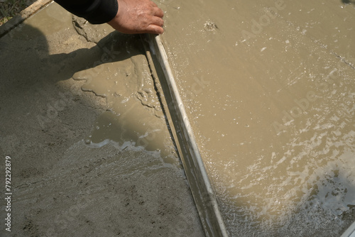 Hand worker spreading flattening on plaster cement mortar.