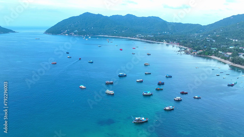 High above the pristine coastline, a drone captures the picturesque scene of numerous fishing boats against the backdrop of tropical splendor. Ko Tao, Surat Thani Province, Southern Thailand.  © Punyawee