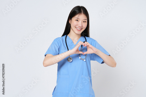 Smiling young woman doctor makes a heart shape with her hand isolate on white background.