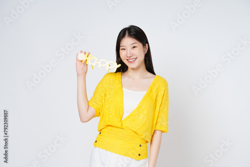 Young asian woman in hand holds HAPPY glasses isolate white background.