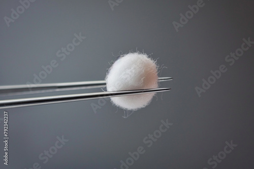 Cotton ball wedged between tweezers