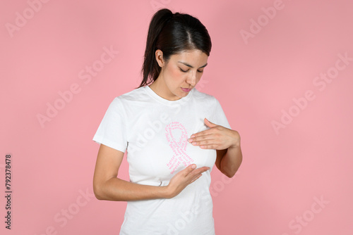 woman explores her breasts in a pink ribbon shirt. concept of fighting breast cancer