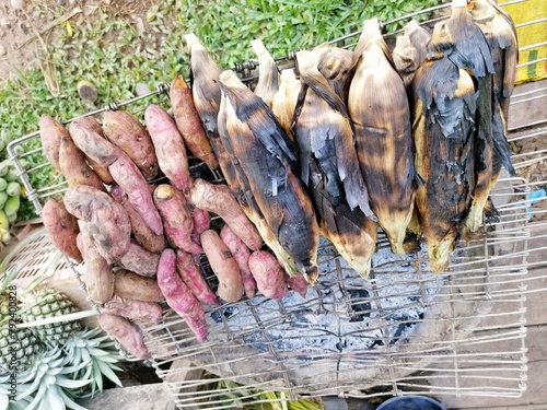 Corn, nuts, and potatoes are burned on a charcoal stove.