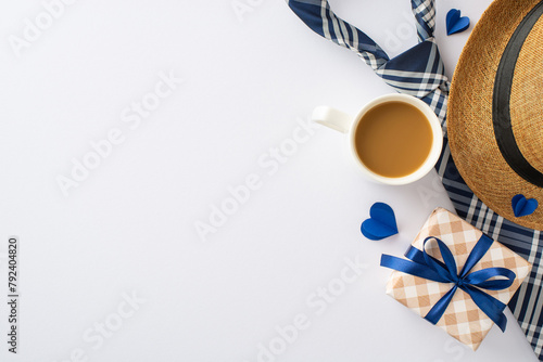 Father's Favorites: Overhead view of a straw hat, dapper necktie, gift box, cup of fresh coffee, and heart cutouts on white. Great for Father's Day wishes or advertisements photo