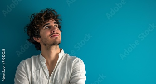 Thoughtful young man with crossed arms exuding confidence gazing upwards with optimism