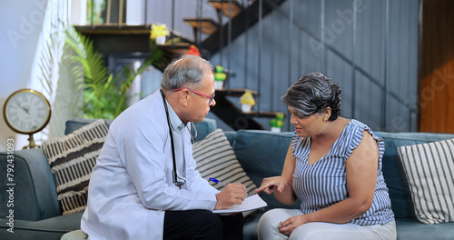 Indian Asian Hindu active gen x older aged doc man male nurse doctor visit old elder senior female house sitting sofa couch chair writing gave ill sick tablet talk drug indoor clinic job medical home