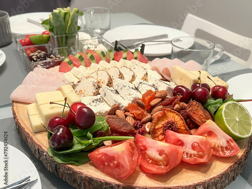 sliced cheese and ham served with fruits and vegetables on the table