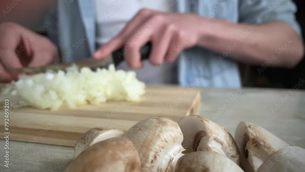 onion slicing, guy cutting onions on wooden board, mushrooms in the foreground, offset focus onion slicing, guy cutting onions on wooden board, mushrooms in the foreground, offset focus