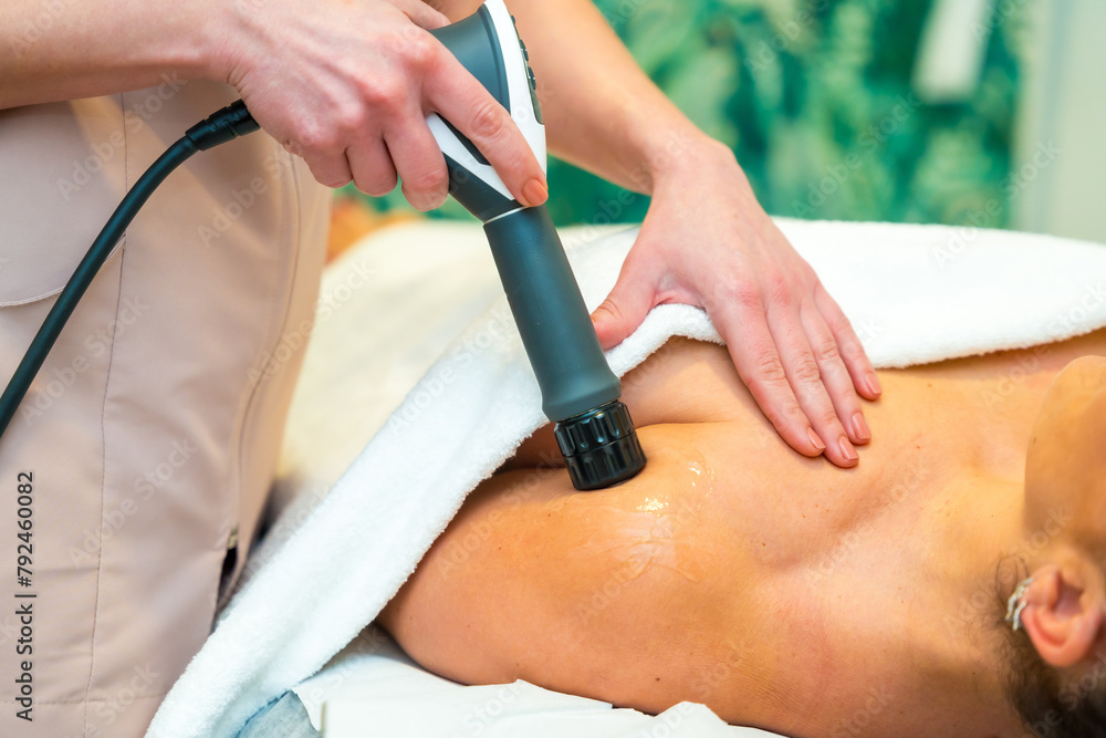 Fototapeta premium Professional masseur treating a patient with innovative shockwaves treatment