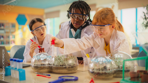 Foto Elementary School Students Sitting Behind a Table in a Group, Conducting a Biology Experiment for a Science and Technology Fair