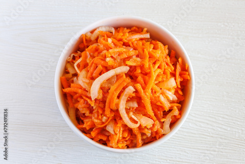 Fresh healthy vegetarian carrot salad with apple, onion and spices in the bowl. Top view, close up