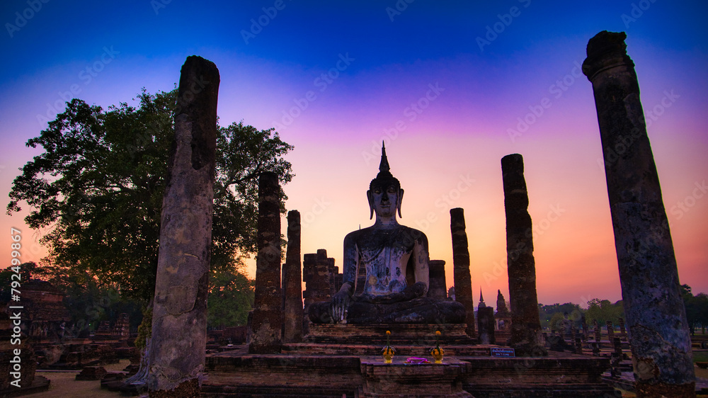 A beautiful sunset over a temple with a statue of Buddha