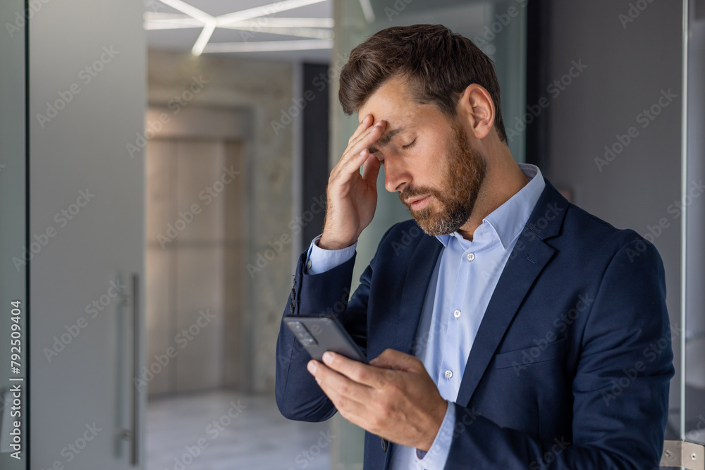 Stressed businessman reading bad news on smartphone Stressed businessman reading bad news on smartphone