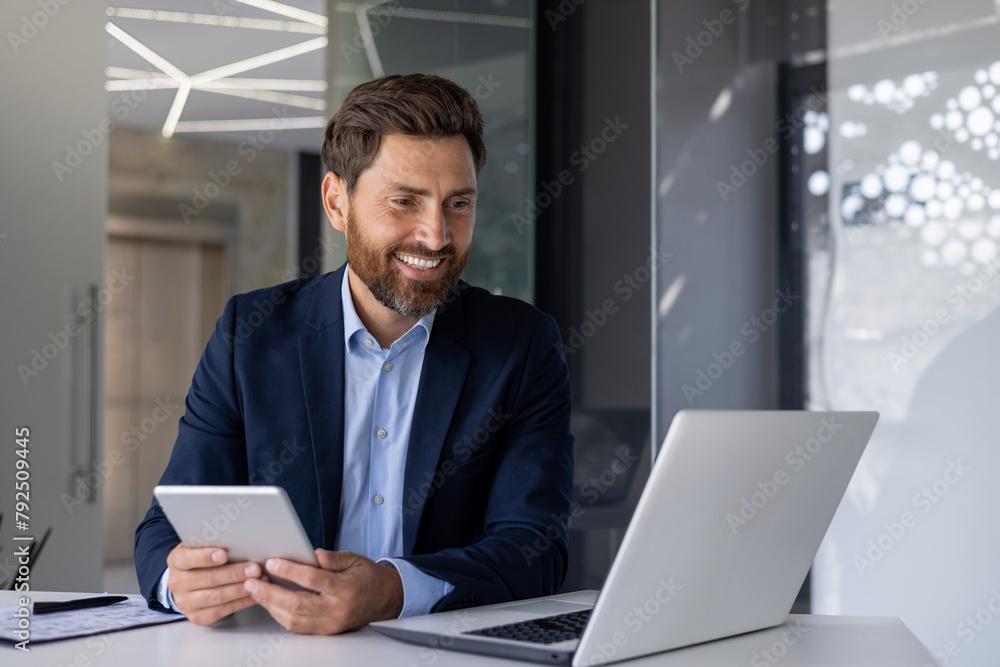 Confident businessman working on laptop and tablet in office Confident businessman working on laptop and tablet in office