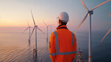 Engineer overlooking offshore wind turbines at sunset