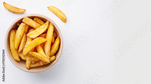Cooked wedges potatoes in a bowl on a white table, top view, space on the right