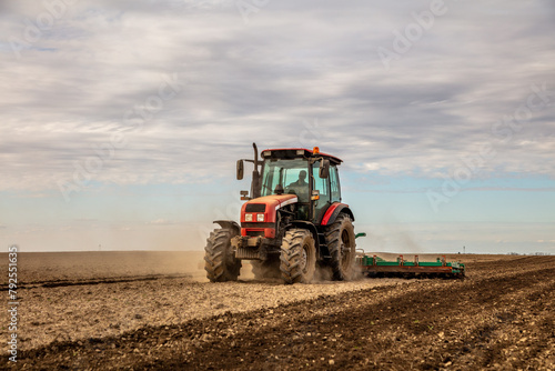 Powerful tractor at work  turning over soil on a vast farmland under a clear sky