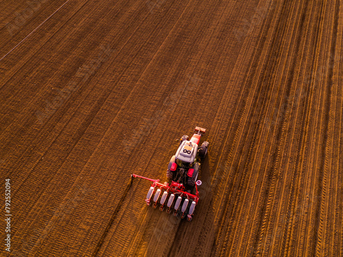 Aerial shot of a farmer seeding, sowing crops at field. Sowing is the process of planting seeds in the ground as part of the early spring time agricultural activities. © oticki