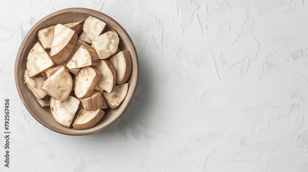 Taro chunks in a bowl on a white table, top view, space on the right Taro chunks in a bowl on a white table, top view, space on the right