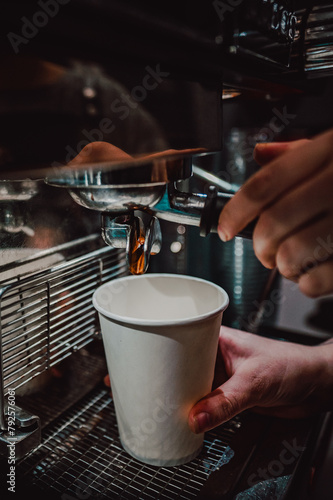 Close-up shot of coffee being poured into a white cup from an espresso machine, capturing the rich color and texture of the coffee