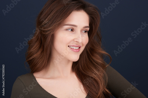 A close-up portrait of a beautiful young woman with pearly white teeth and green eyes looking off-camera.