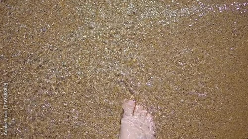 Close-up of feet splashing in the shallow beach waters in slow motion 300fps photo