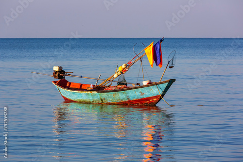 A single small fishing boat rest on the calm sea in the morning light in the eastern Gulf of Thailand.