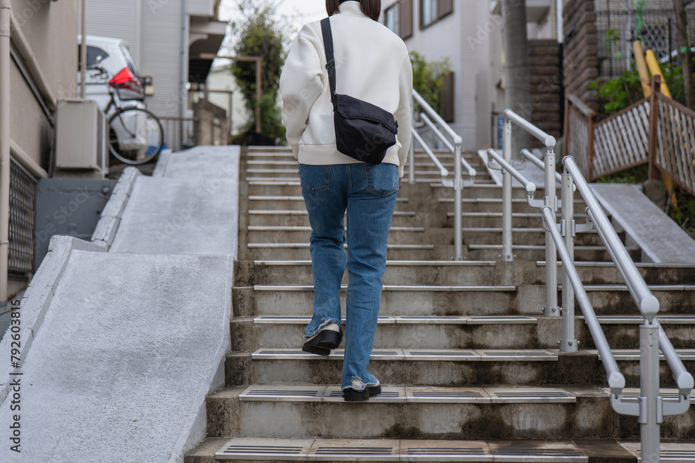 住宅街の坂道を上る女性のうしろ姿 住宅街の坂道を上る女性のうしろ姿