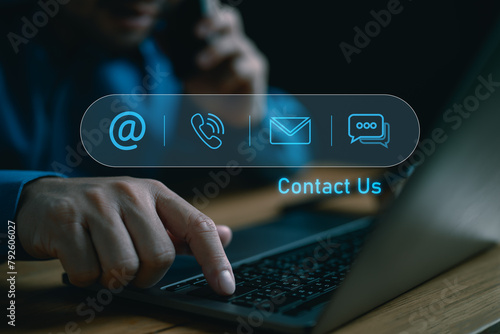 Contact us or Customer support hotline people connect. Businessman using a laptop with virtual screen contact icons ( email, address, live chat, phone ). © Looker_Studio