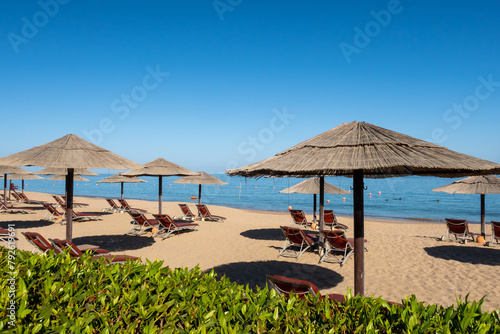 Sandy beach in Fujairah, United Arab Emirates, with thatch umbrellas and sunbeds, sea view and blue sky, no people.