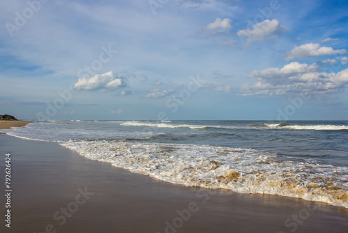Beautiful seascape with waves on the sandy beach in summer with blue cloudy sky. Scenic Landscape wallpaper. Udupi Karnataka India