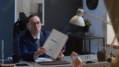 Medium shot of male office worker searching for missing presentation page on desk, nasty colleague holding document up, taunting and teasing him photo
