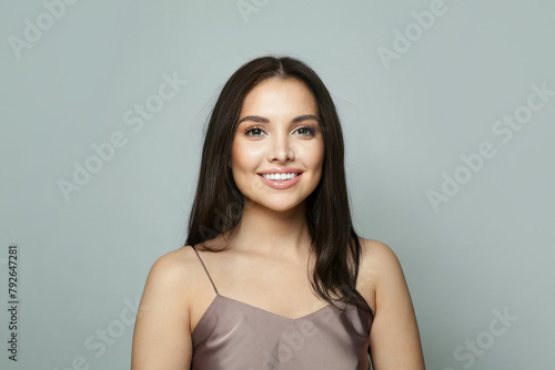 Cheerful healthy female model with clean skin, make-up and perfect hairstyle against white studio wall background © artmim