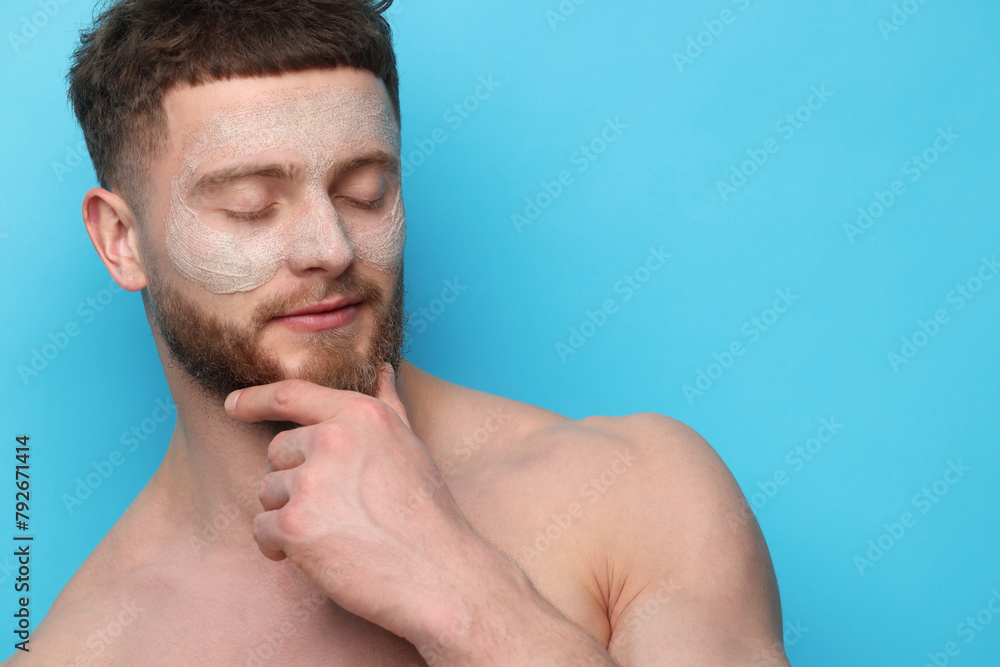 Naklejka premium Handsome man with facial mask on his face against light blue background