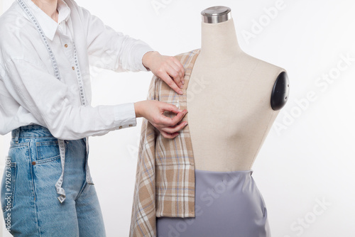 The couturier's tailor works with a mannequin on a white background
