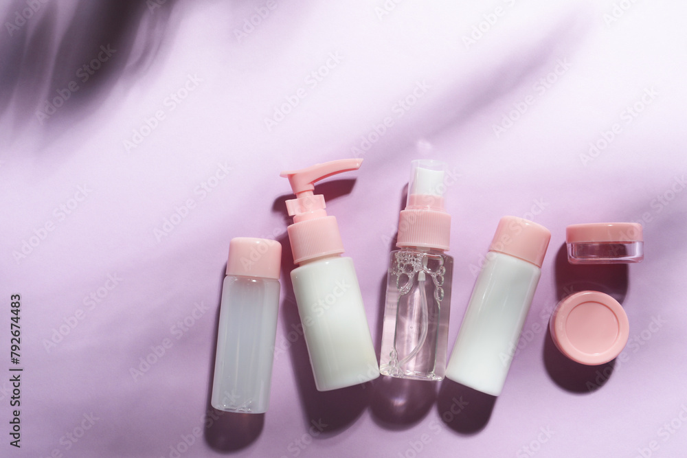 Cosmetic travel kit on violet background, top view. Space for text Cosmetic travel kit on violet background, top view. Space for text