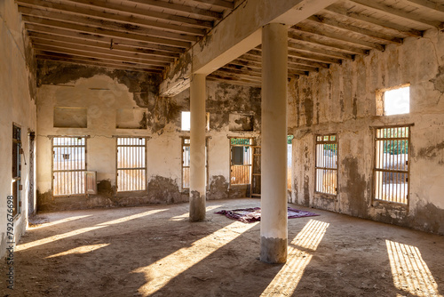 Inside of demolished abandoned mosque in Al Jazirah Al Hamra haunted town in Ras Al Khaimah, United Arab Emirates, neglected walls, columns, bars on the windows and old muslim prayer rug.