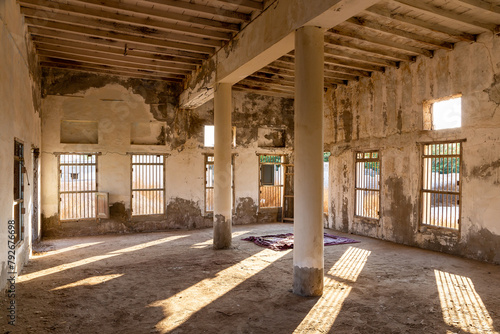 Inside of demolished abandoned mosque in Al Jazirah Al Hamra haunted town in Ras Al Khaimah, United Arab Emirates, neglected walls, columns, bars on the windows and old muslim prayer rug. photo