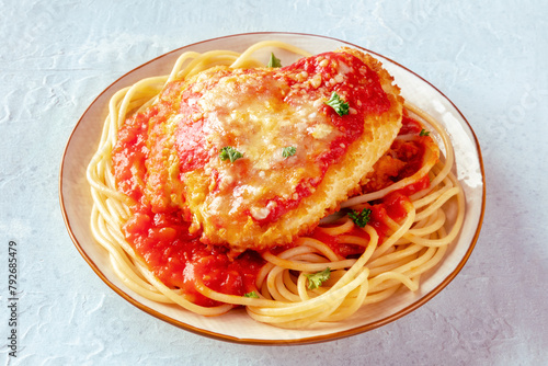Chicken Parmesan, Italian pasta dish. Breaded chicken breast with cheese and spaghetti with tomato sauce, on a slate background