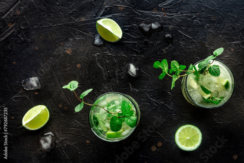 Mojito cocktail. Summer cold drink with lime, fresh mint, and ice. Cool beverage on a black slate background, shot from the top
