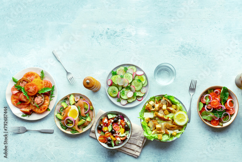Fresh salads, overhead flat lay shot of an assortment. Variety of plates and bowls with green vegetables. Healthy food, shot from above with a place for text