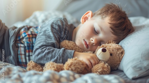 A peaceful boy sleeping snugly with a teddy bear in a comfortable bed, depicting restful childhood sleep. photo