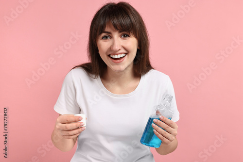 Young woman with mouthwash on pink background