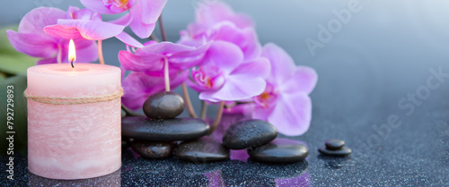 Spa background with pink orchid , candle and zen black stones on gray.
