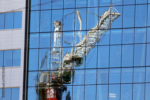 Reflet d'une grue sur une bâtiment vitré sur un chantier de construction	